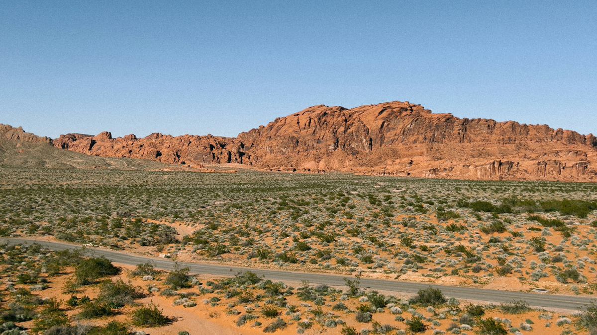 Remote desert road through vacant land in the American West, illustrating access and landlocked property considerations for buyers.