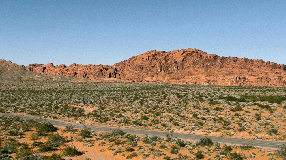 Remote desert road through vacant land in the American West, illustrating access and landlocked property considerations for buyers.