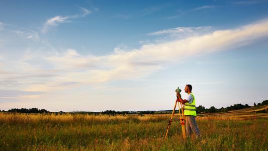 Surveyor measuring land boundaries on a vacant rural parcel.
