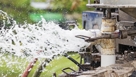 Water well drilling rig spraying water during a successful well installation