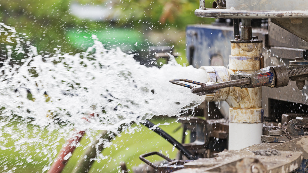 Water well drilling rig spraying water during a successful well installation